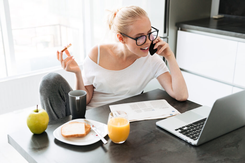 woman enjoying a protein bar while working at a desk