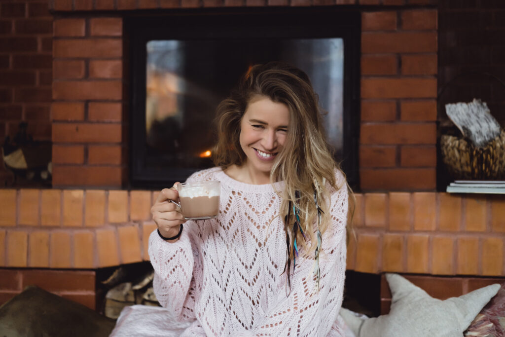 cozy winter lifestyle woman with blanket holding mug of hot chocolate
