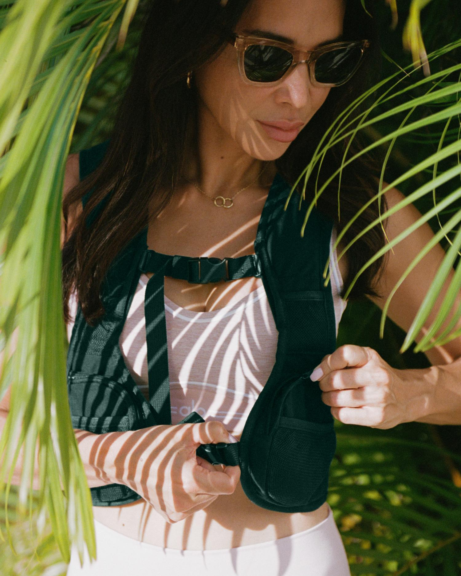 Product image prompt: a premium weighted vest (Warrior Vest) displayed on a minimal mannequin torso or flat-lay on a neutral surface; removable iron-sand pouches shown neatly beside it to illustrate adjustable weight system; clean, modern design details visible (Cordura texture, reinforced stitching, breathable mesh); diffused flattering light, film-inspired low contrast, ultra-realistic editorial product photography.